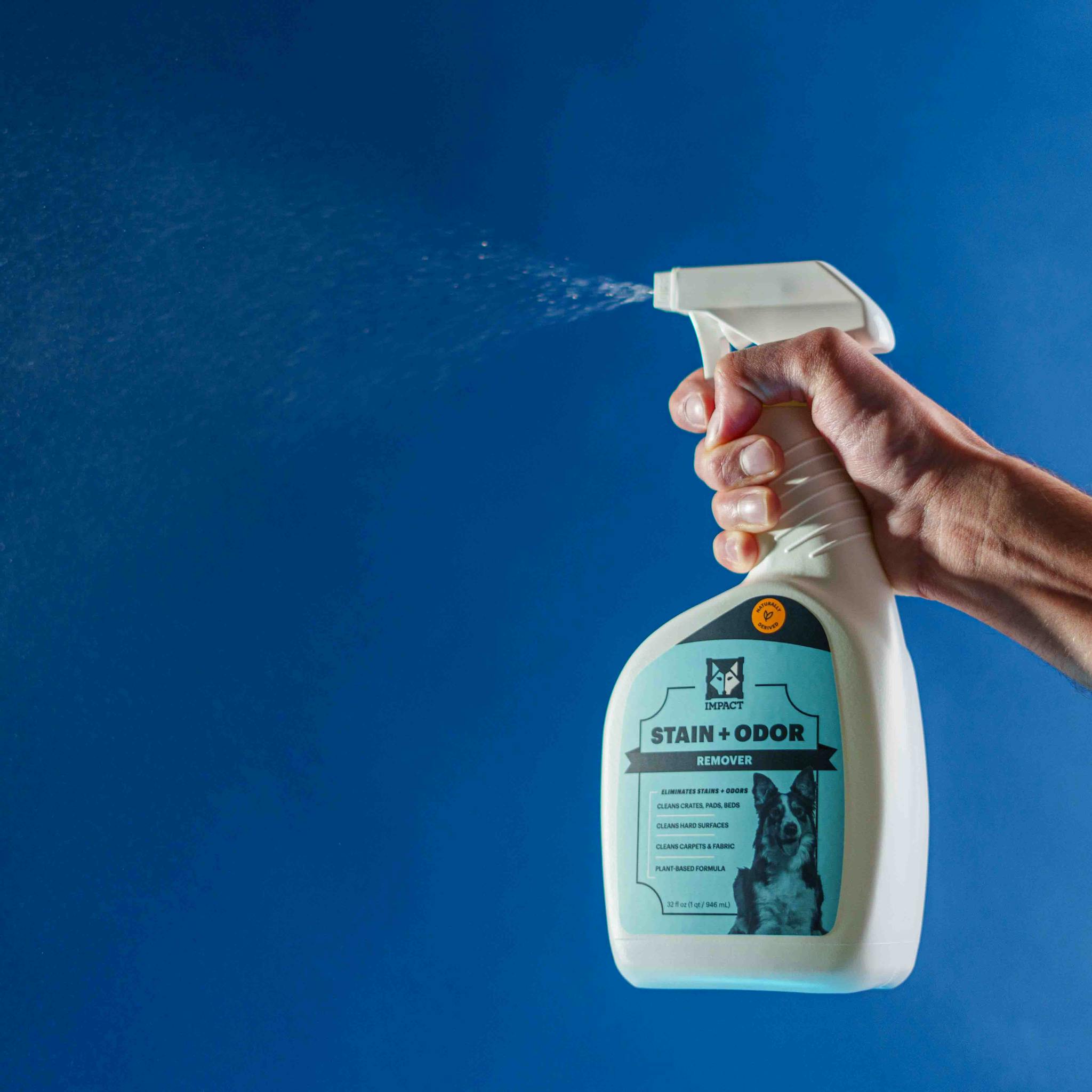 High-quality pet stain and odor remover spray bottle in use against a blue background.